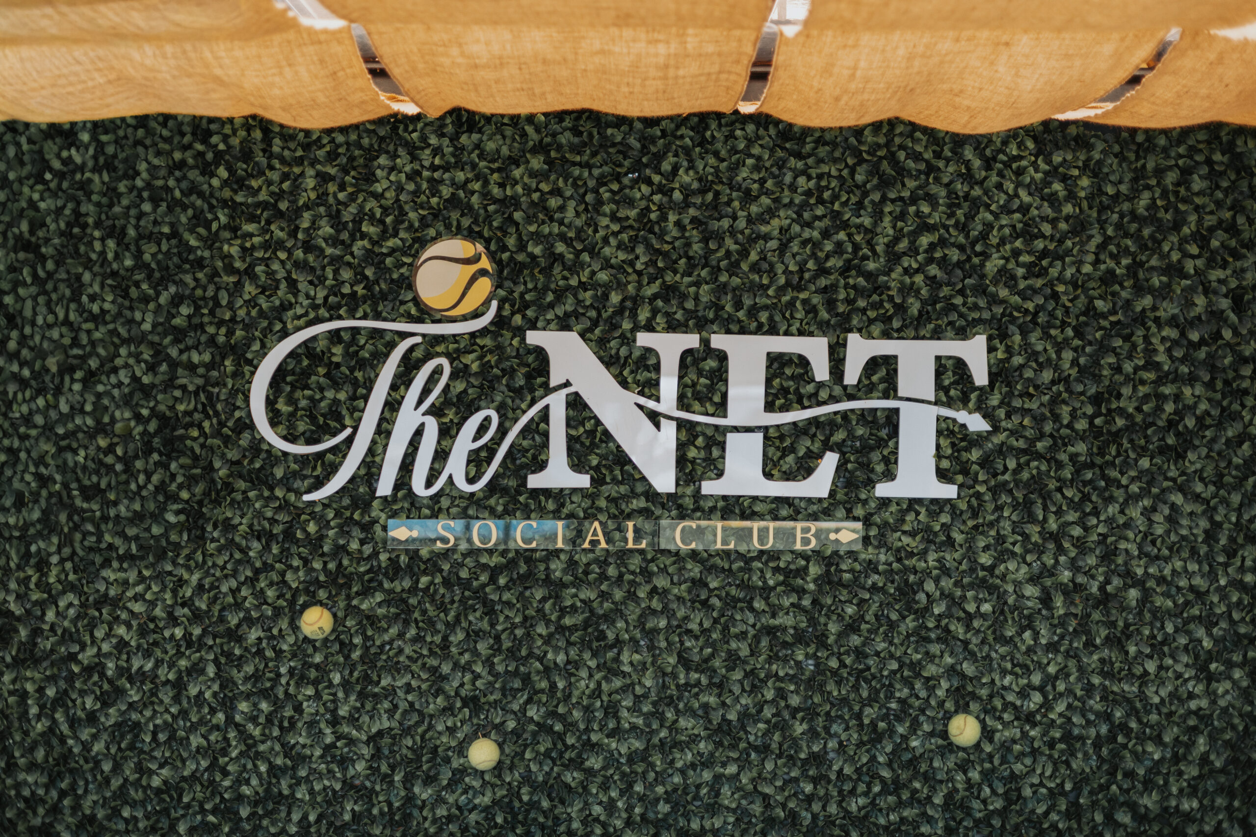 The Net Social Club branding wall with padel theme background